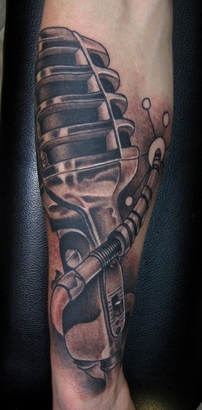 Black and grey Vintage Microphone arm tattoo start to a full music theme 